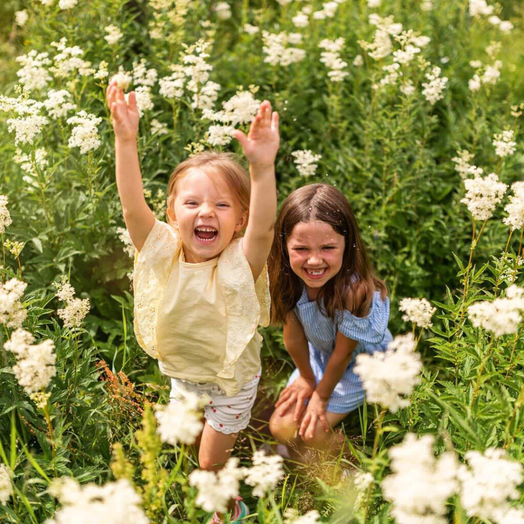 Busiga barn under en familjefotografering som kastar blomblad i hög vegitation