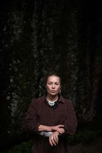 porträtt av en ung kvinna i brun skjorta och stort silverhalsband