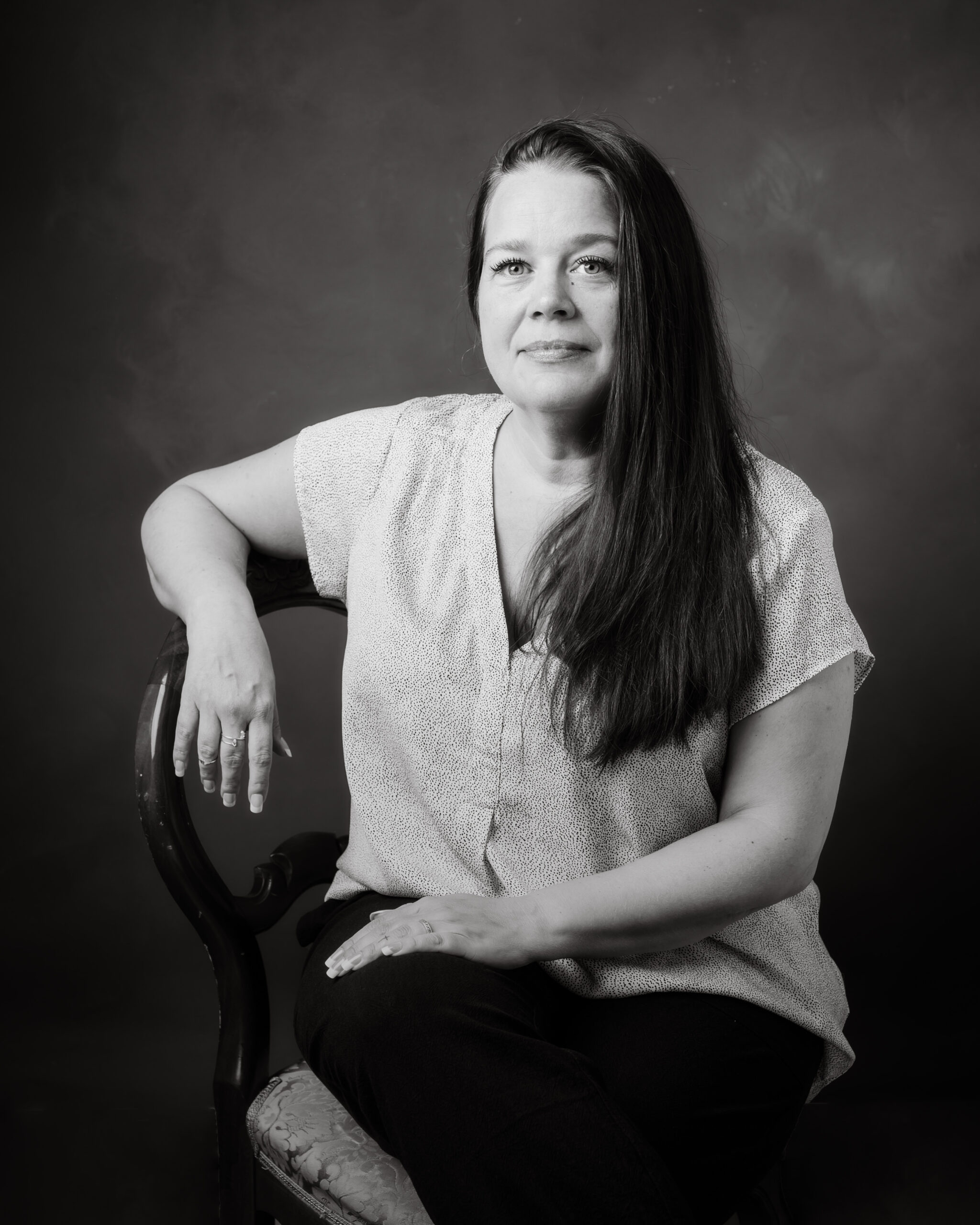 en kvinna i "30 över 30" projektet sitter på en stol och tittar avslappnat in i kameran